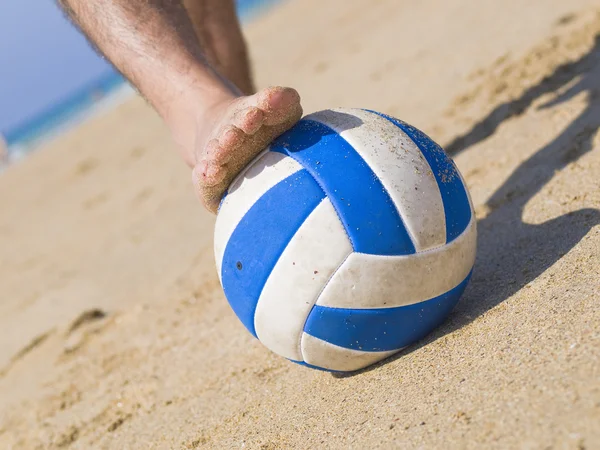 Foot stepping on a ball on the beach 2 Stock Image