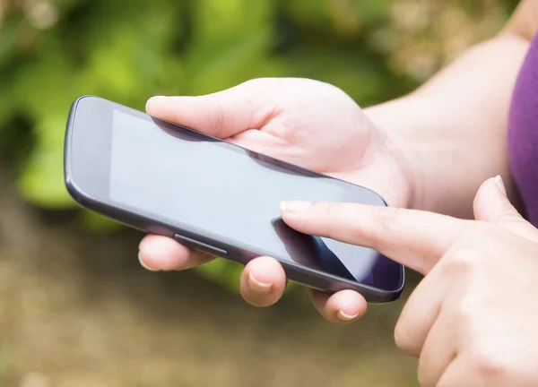 Modern cep telefonu ekranında kadın eli değmiş.