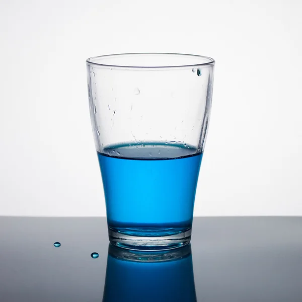 Vidro meio cheio de líquido azul — Fotografia de Stock