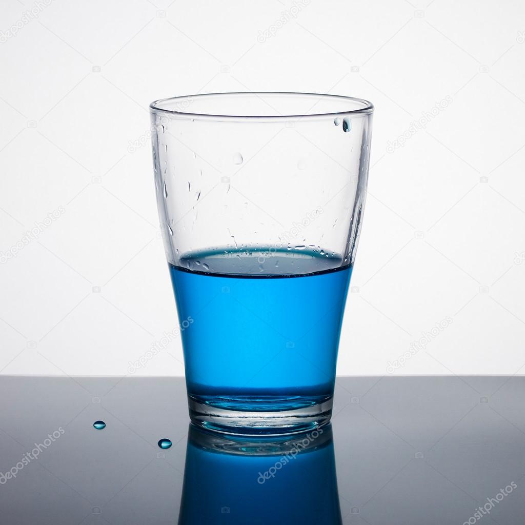 Glass half full of blue liquid