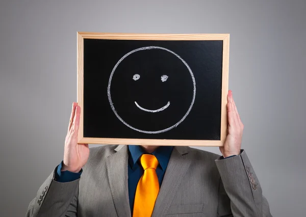 Zakenman verbergen van zijn gezicht met een zwarte bord met een smiley — Stockfoto