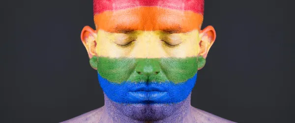 Bandeira gay pintada no rosto de um homem . — Fotografia de Stock