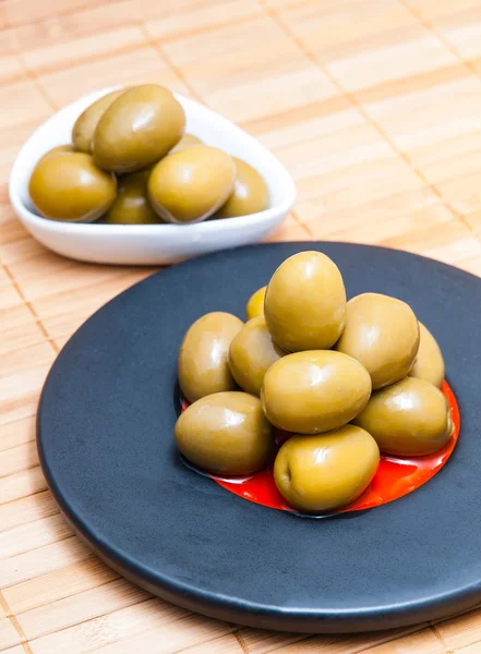 Olives in a black plate and in a white container — Stock Photo, Image