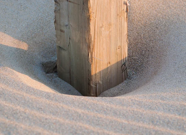 Wooden post buried in the sand — Stock Photo, Image