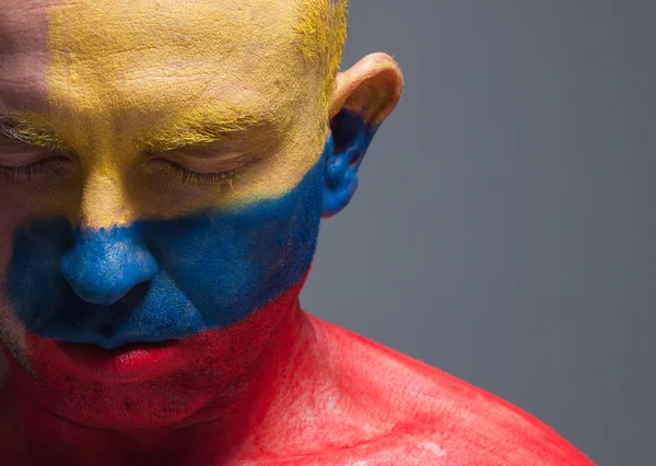 Homem e seu rosto pintado com a bandeira da Colômbia . — Fotografia de Stock