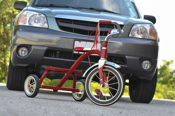 Triciclo infantil na frente do SUV — Fotografia de Stock