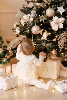 Küçük bir kız ilk yılbaşında bir Noel ağacı süslüyor.