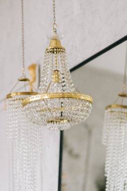 Oturma odasında altın işlemeli büyük kristal cam avize.