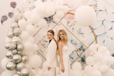 Yuvarlak bir fotoğraf bölgesinin arka planında, bir olay için beyaz topları olan iki güzel sarışın kız.