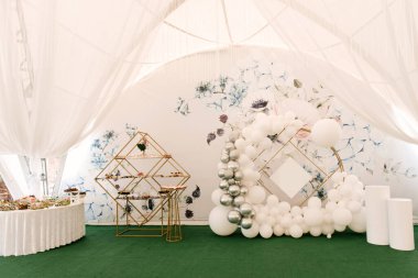 Bir olay ya da doğum günü için beyaz ve gümüş topların olduğu yuvarlak fotoğraf bölgesi ve çadırda açık büfe.