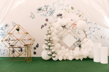 Bir olay ya da doğum günü için beyaz ve gümüş topların olduğu yuvarlak fotoğraf bölgesi ve çadırda açık büfe.