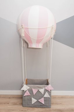 İçinde pembe balon, çocuk odası ve tatil dekoru olan sepet.