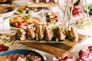 Güzel dekore edilmiş yemek sofrası farklı atıştırmalıklar ve sandviçli aperatifler şirket partisinde taze meyveler ya da düğün kutlamaları.