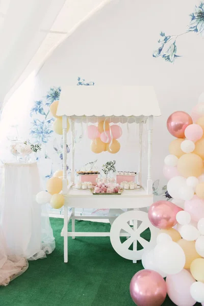 Beautiful candy bar decor with homemade craft marshmallows and cupcakes in a wooden white cart