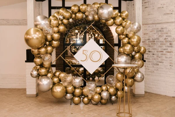 The round photo zone is decorated with gold and silver balls for the 50th birthday, the work of an aerodesigner