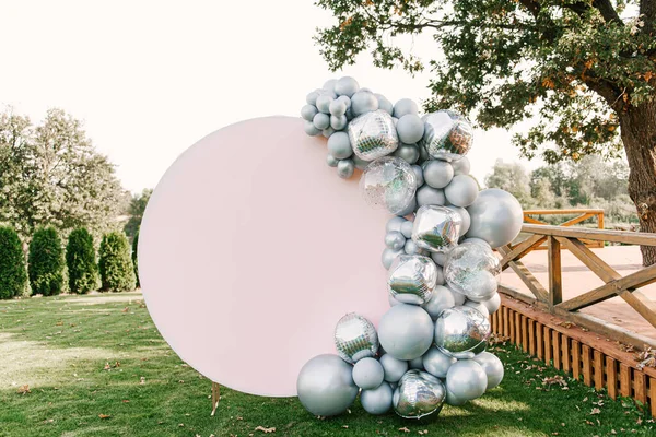 Metnini kopyalamak için boşluğu olan gümüş balonlardan oluşan yuvarlak pembe fotoğraf bölgesi. Parti balonlarla süslenmiş.