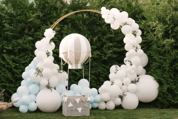 Tatil partisi için dekorasyon. Bir sürü balon mavi ve beyaz renkli. Yuvarlak fotoğraf bölgesi, topların yanında bir çocuk için sepeti var.