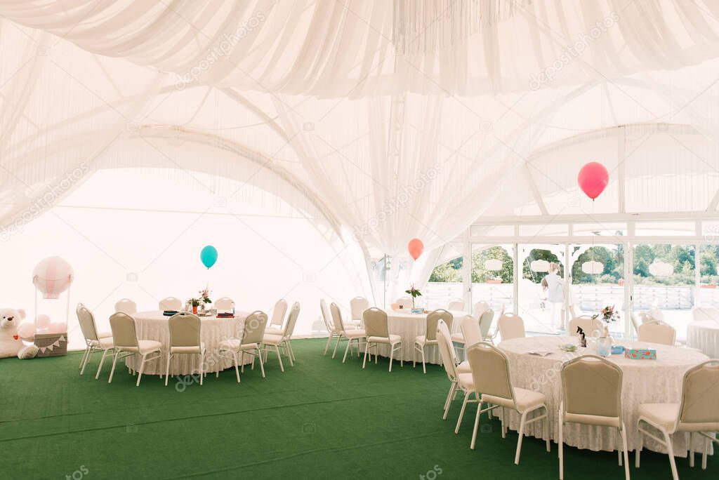 Tables in a large white tent with a balloon