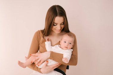 Sevgi dolu genç anne ve yeni doğmuş kızı açık bir arka planda.