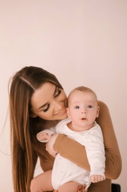 Sevgi dolu genç anne ve yeni doğmuş kızı açık bir arka planda.