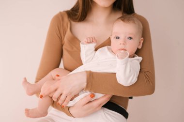 Sevgi dolu genç anne ve yeni doğmuş kızı açık bir arka planda.