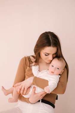 Sevgi dolu genç anne ve yeni doğmuş kızı açık bir arka planda.