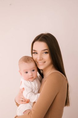 Sevgi dolu genç anne ve yeni doğmuş kızı açık bir arka planda.