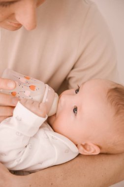 Kafkasyalı baba yeni doğmuş bebeği şişeden besliyor. Anne ve baba, sallanan kız evlat oğlunu ellerinde tutuyor. Otantik yaşam tarzı ebeveynlik anı.