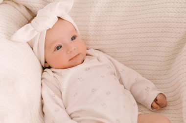 Beyaz elbiseli, beyaz arka planda tatlı yeni doğmuş kız.