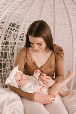 Sevgi dolu genç anne ve yeni doğmuş kızı açık bir arka planda.