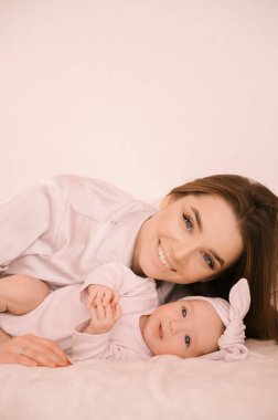 Sevgi dolu genç anne ve yeni doğmuş kızı açık bir arka planda.