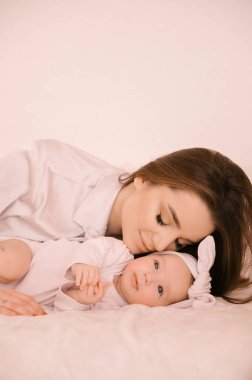 Sevgi dolu genç anne ve yeni doğmuş kızı açık bir arka planda.