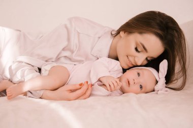 Sevgi dolu genç anne ve yeni doğmuş kızı açık bir arka planda.