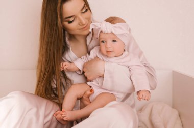 Sevgi dolu genç anne ve yeni doğmuş kızı açık bir arka planda.