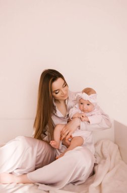 Sevgi dolu genç anne ve yeni doğmuş kızı açık bir arka planda.