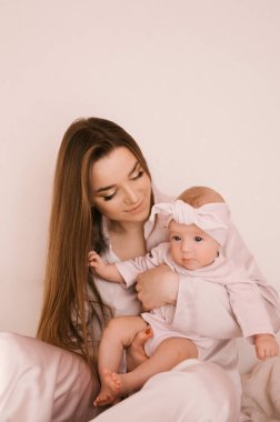 Sevgi dolu genç anne ve yeni doğmuş kızı açık bir arka planda.