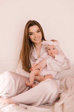 Sevgi dolu genç anne ve yeni doğmuş kızı açık bir arka planda.