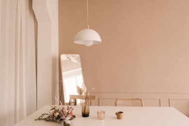 Modern iç tasarım. Rahat kanepe, sehpa, çiçekler, tablolar ve beyaz duvarlarla dekore edilmiş şık bir oturma odası. Kiralık minimalist bir daire.