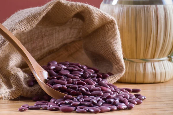 Haricots rouges dans une cuillère et un sac en bois — Photo