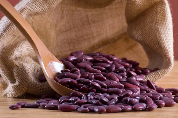 Red beans in a wooden spoon and bag — Stock Photo, Image