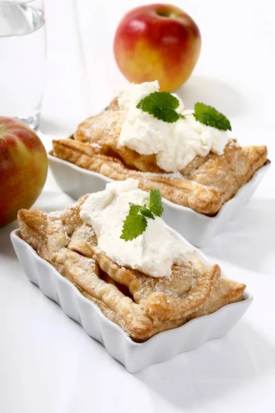 Apple pies with cream and lemon balm in small baking trays