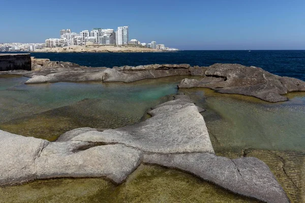 Bizarre rocky coast with natural water basins, view of Sliema, Valletta, Malta, Europe