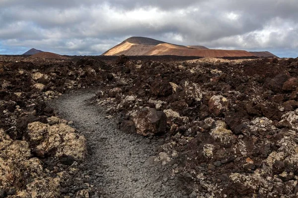 Path through a lava field, volcanic landscape, Fire Mountains, volcanoes, Caldera Blanca volcano at the back, Lanzarote, Canary Islands, Spain, Europe
