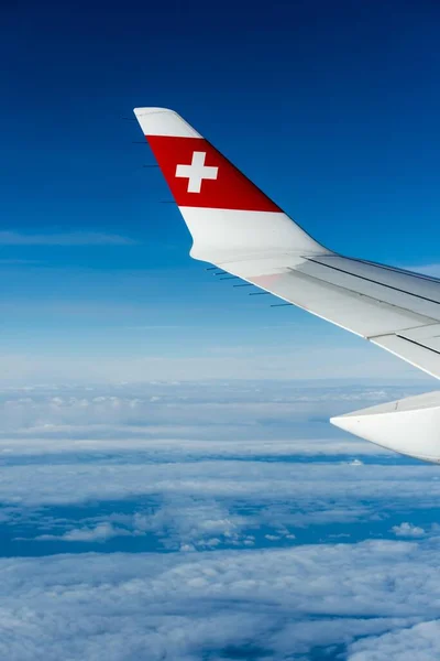 スイス航空のロゴとボンバルディアCs300の翼 輸送機 雲の上 — ストック写真