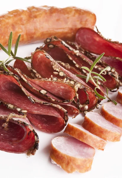 Embutido de carne en rodajas sobre fondo blanco con hierbas y especias — Foto de Stock