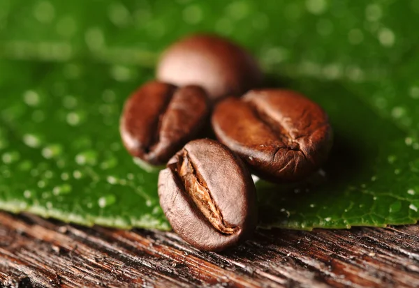 Granos de café y hojas en el fondo de madera —  Fotos de Stock