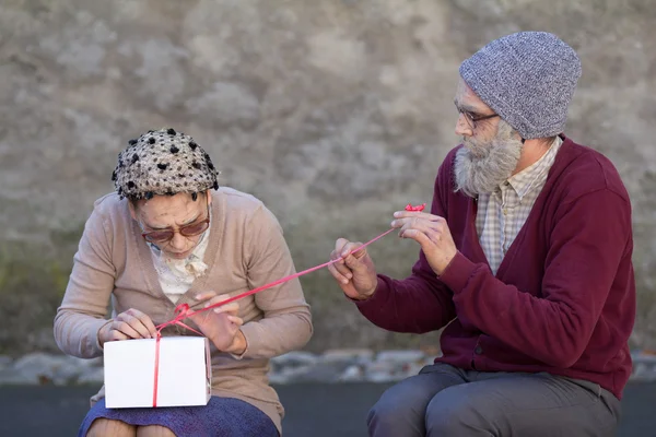 Old street performer opening a present.. — Stock Photo, Image