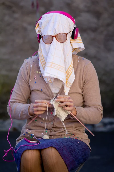 Mulher velha tricô com uma toalha de prato no rosto . — Fotografia de Stock