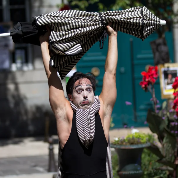 Clown hebt einen gestreiften Sonnenschirm. — Stockfoto