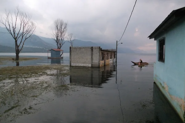 Hombre en un pequeño bote en una zona inundada del pueblo — Foto de Stock